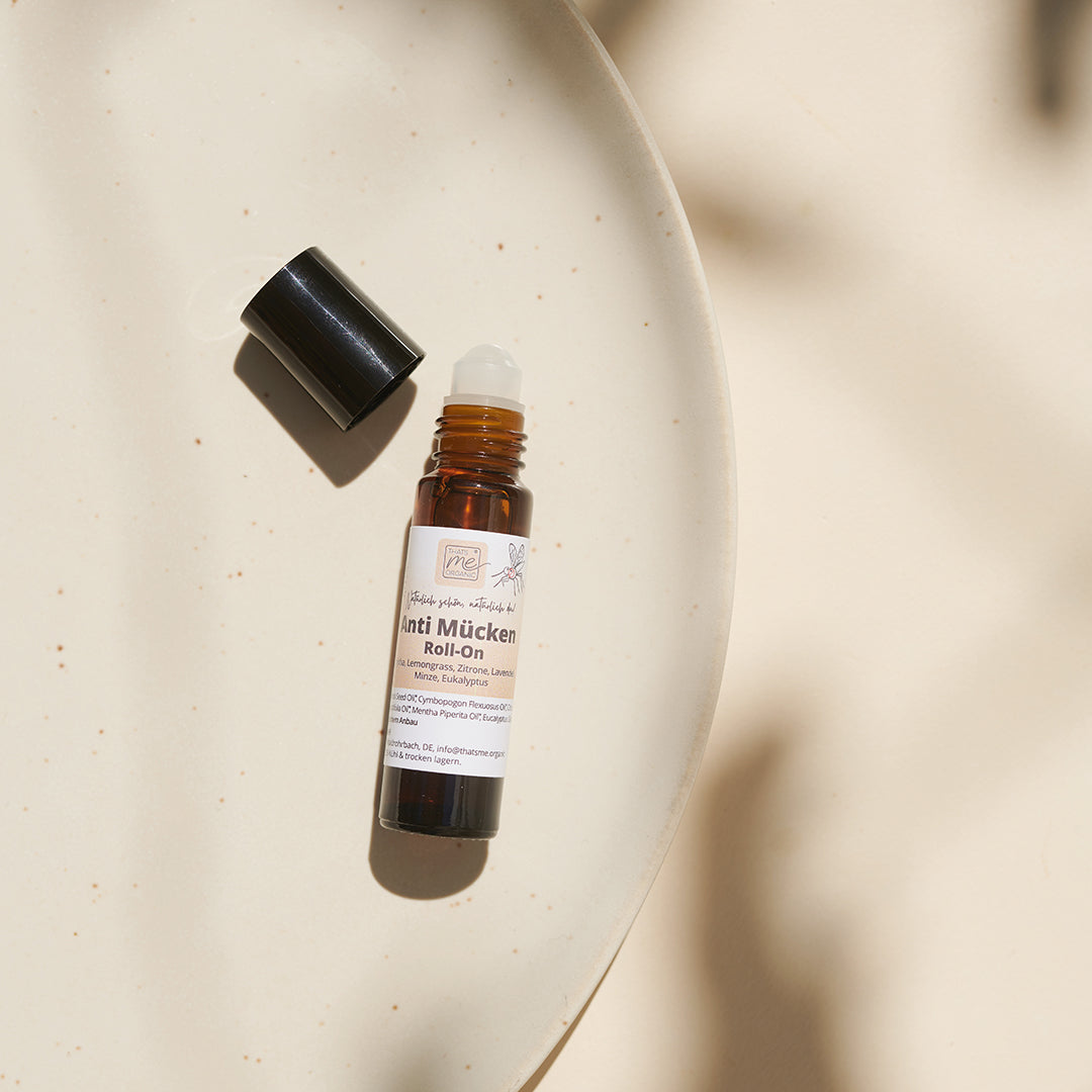 Thats me Organic® Brown Anti-Mücken-Roll-On mit schwarzer Kappe auf beiger Keramikplatte in natürlichem Licht - Ihr natürlicher Mückenschutz und praktisches Hausmittel gegen Mücken.