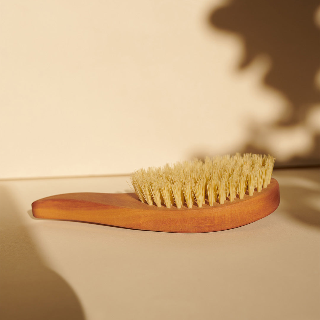 Die Thats me organic® vegane Haarbürste mit natürlichen Sisal-Borsten liegt auf beiger Oberfläche im sanften Licht mit zarten Schatten - ideal zur Förderung des Haarwachstums.