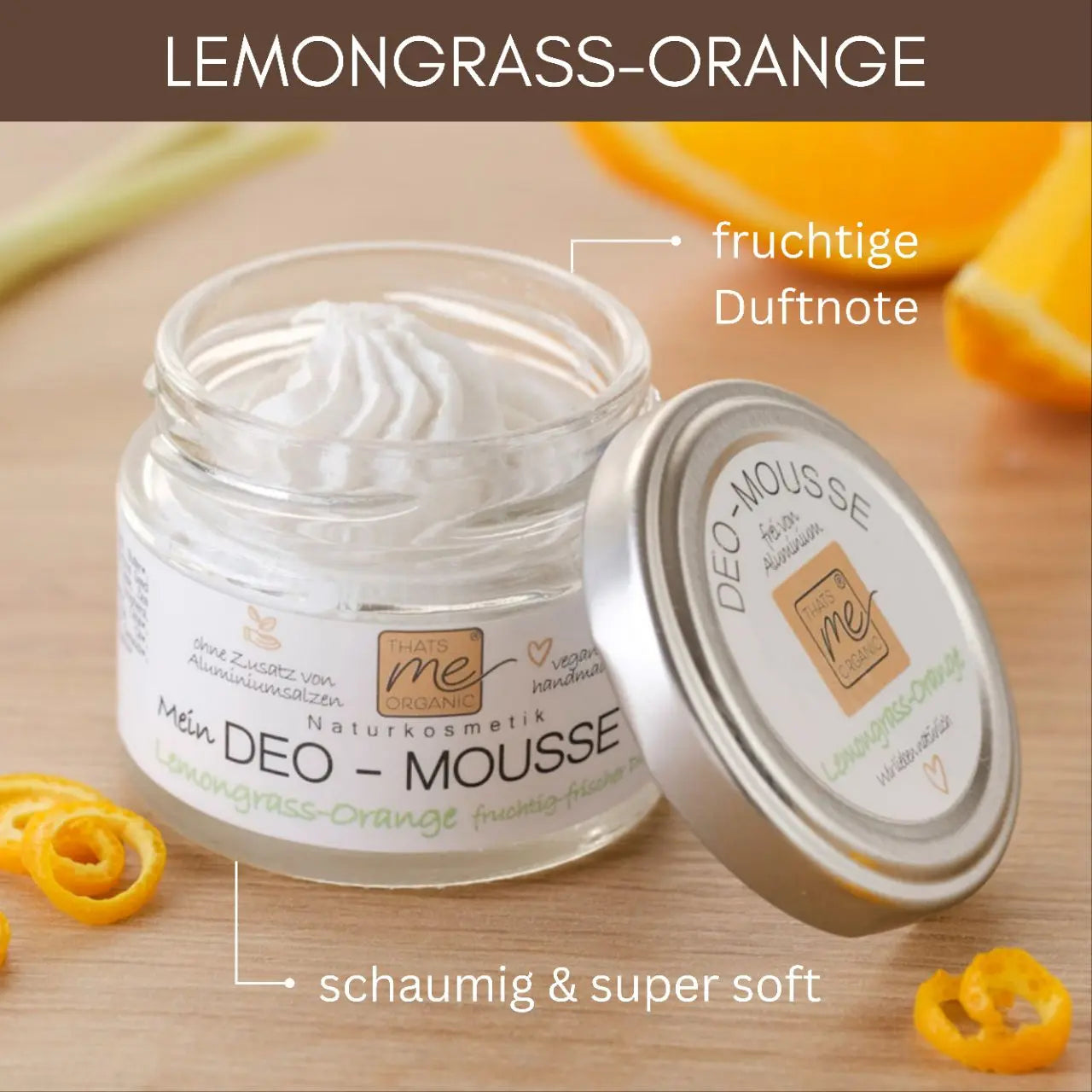 Ein geöffneter Tiegel Thats me Organic® Bio-Deo Deo-Mousse mit Orangenscheiben und -schalen im Hintergrund unterstreicht die natürliche Frische dieses Bio-Deos.