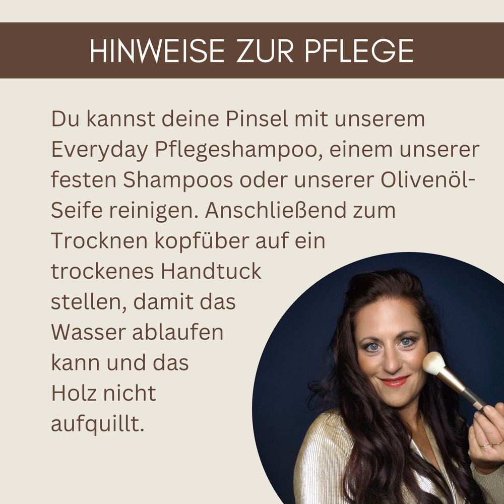 Frau mit langen braunen Haaren hält einen veganen Make-up-Pinsel von Thats me Organic® vor ihrem Gesicht und lächelt vor dunkelblauem Hintergrund.