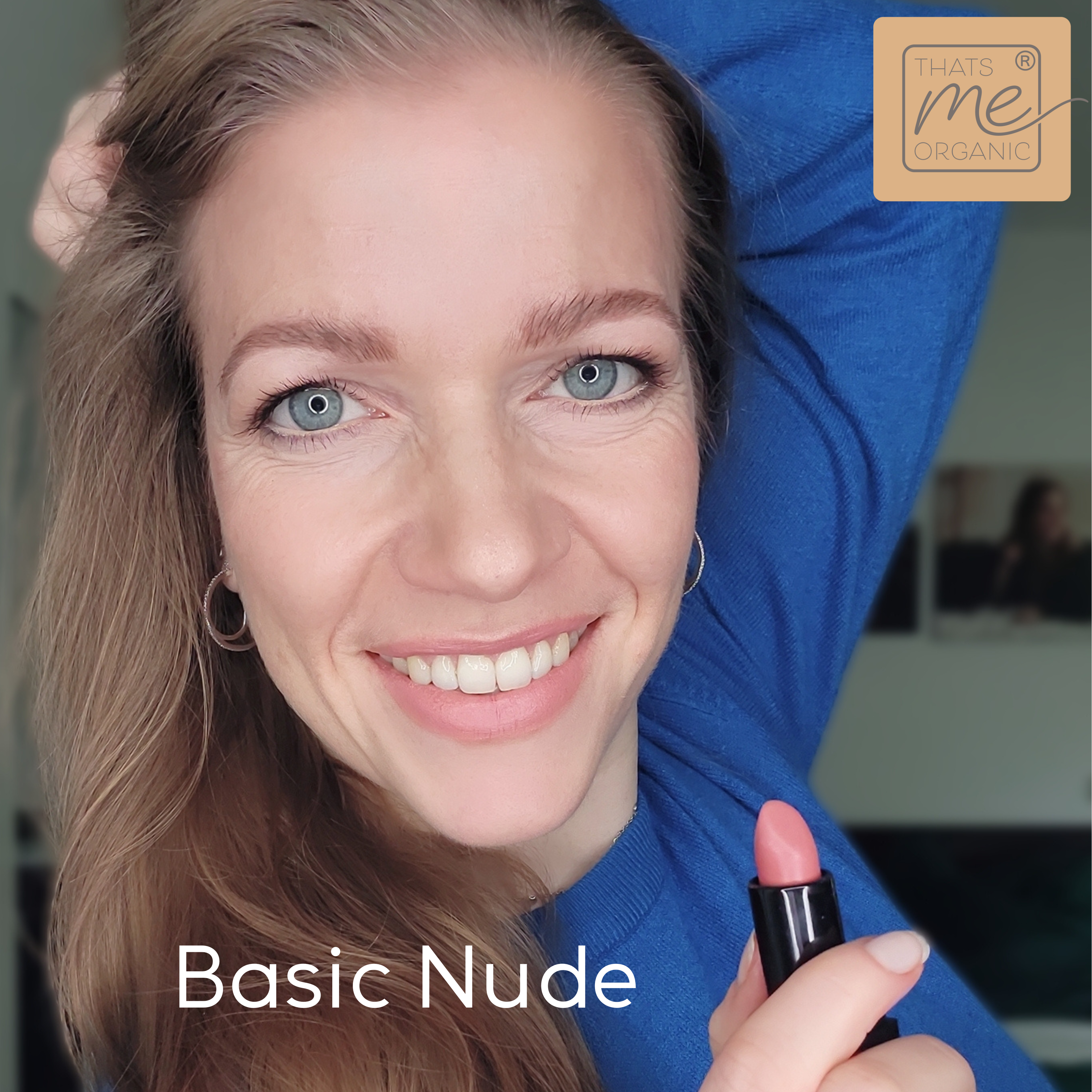 Eine lächelnde Frau hält einen nudefarbenen Lippenstift mit dem Schriftzug "Basic Nude" und "Thats me Organic®" in der Ecke - ein Hinweis auf vegane Bio-Lippenstifte für natürliche Lippenpflege.