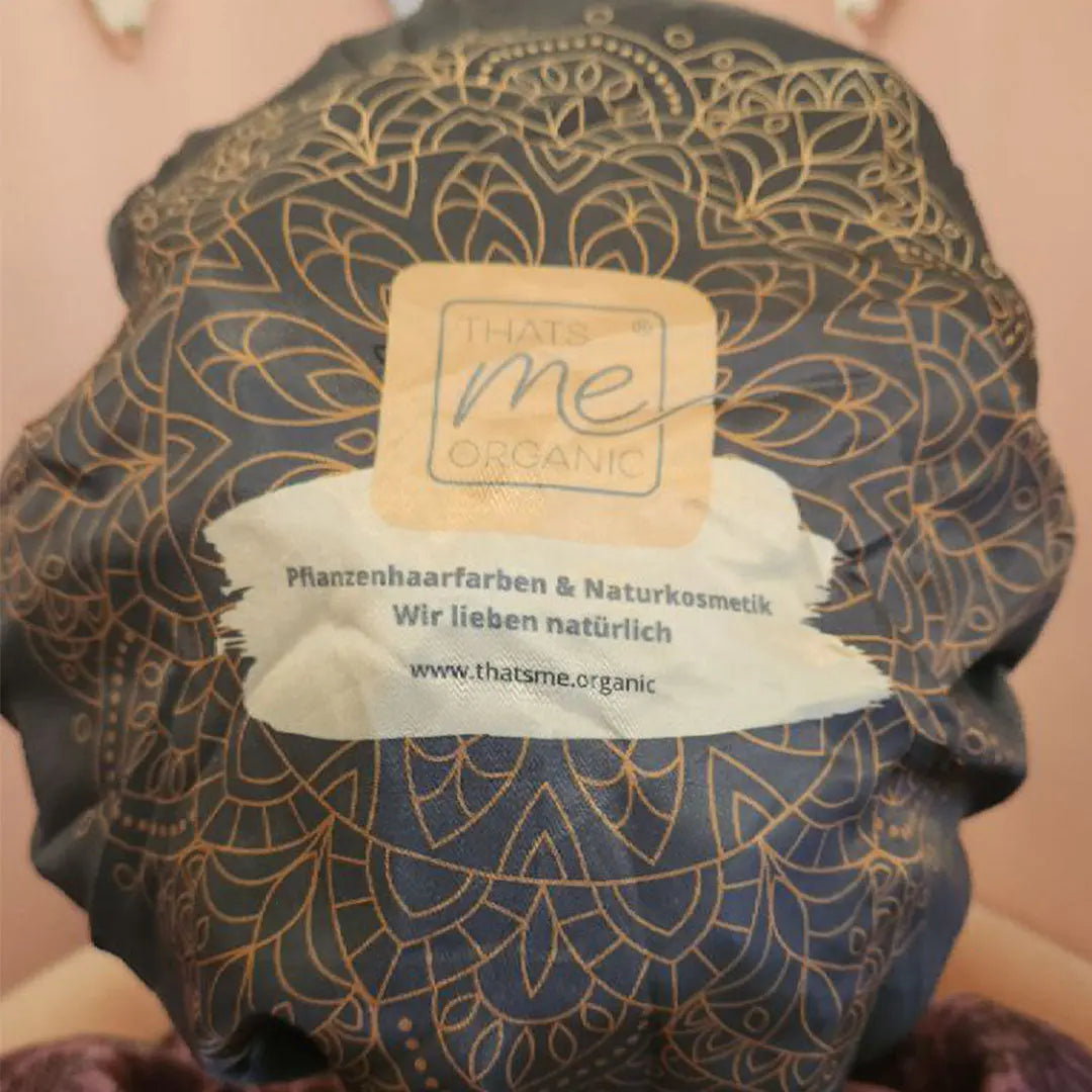 Nahaufnahme einer gemusterten Duschhaube für die Curly-Girl-Methode mit dem Thats me Organic®-Branding und einem deutschen Text, der Naturkosmetik hervorhebt.
