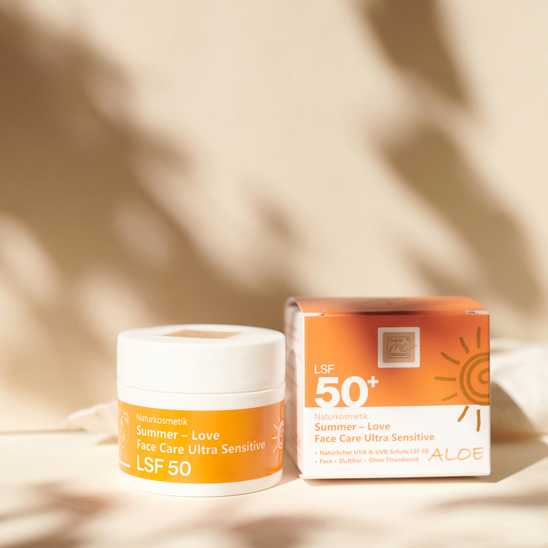 Ein Tiegel und eine Dose Thats me Organic® Summer - Love Face Care Ultra Sensitive Sonnencreme LSF 50+ mit UVA- und UVB-Schutz, titandioxidfrei, auf beiger Oberfläche.