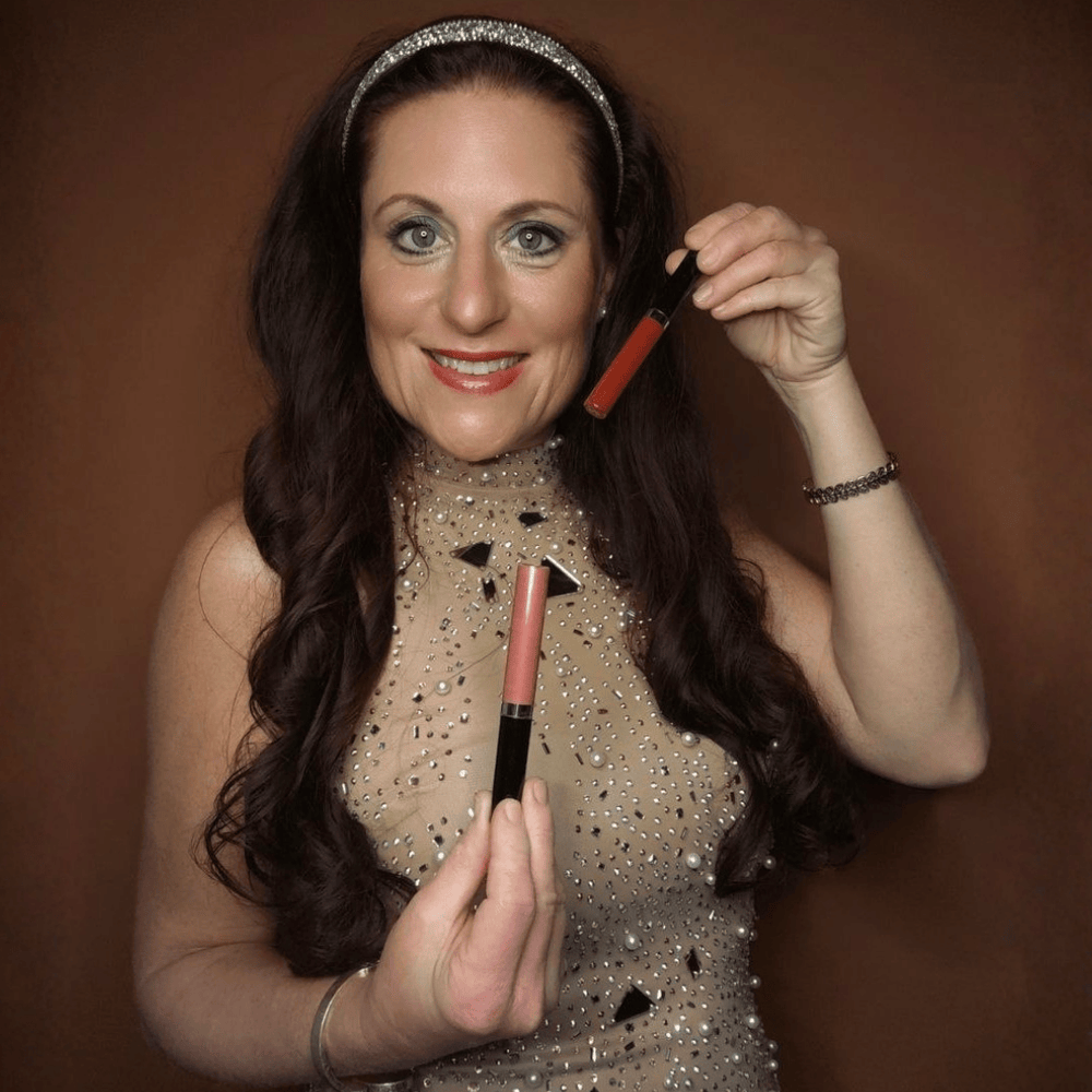 Model hält zwei Lipglosse in Rot und Peach und zeigt die Farben in der Anwendung