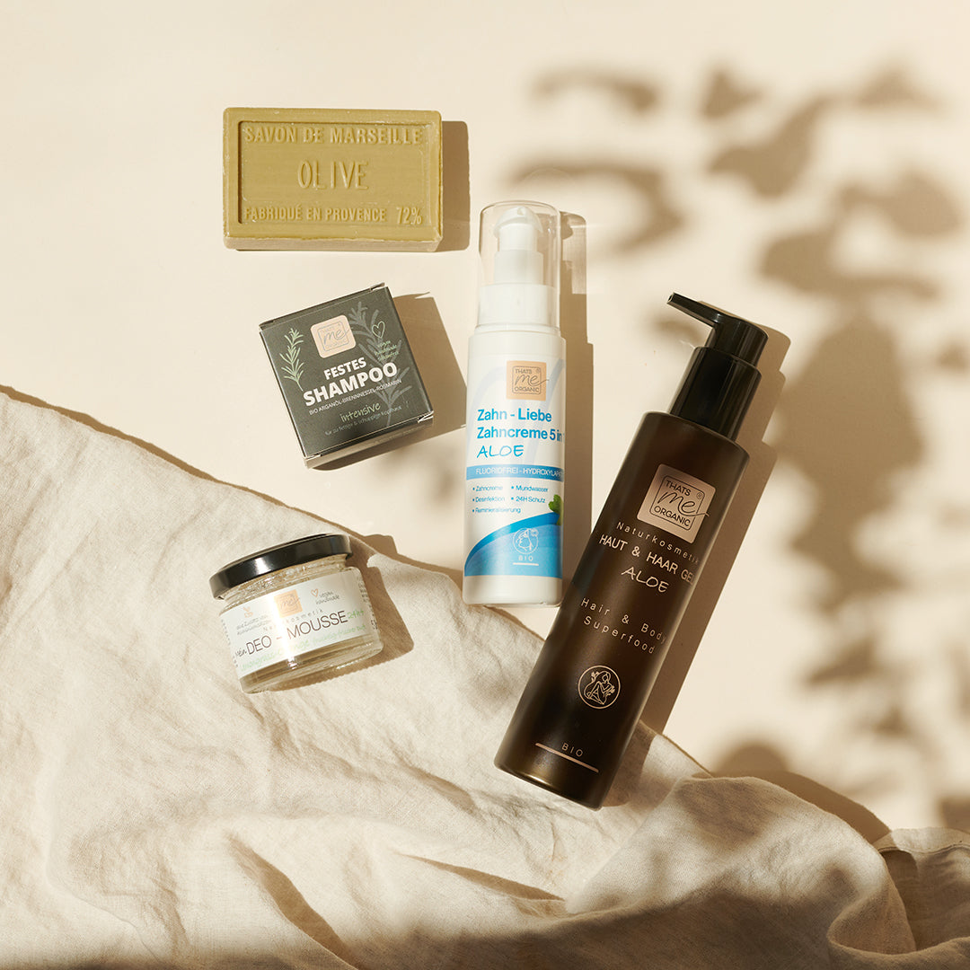 Thats me Organic® Hautpflege- und Hygieneprodukte, wie Deo-Mousse, ausgestellt auf einem neutralen Tuch im Sonnenlicht - perfekt als Geschenk Set für natürliche Männerpflege.