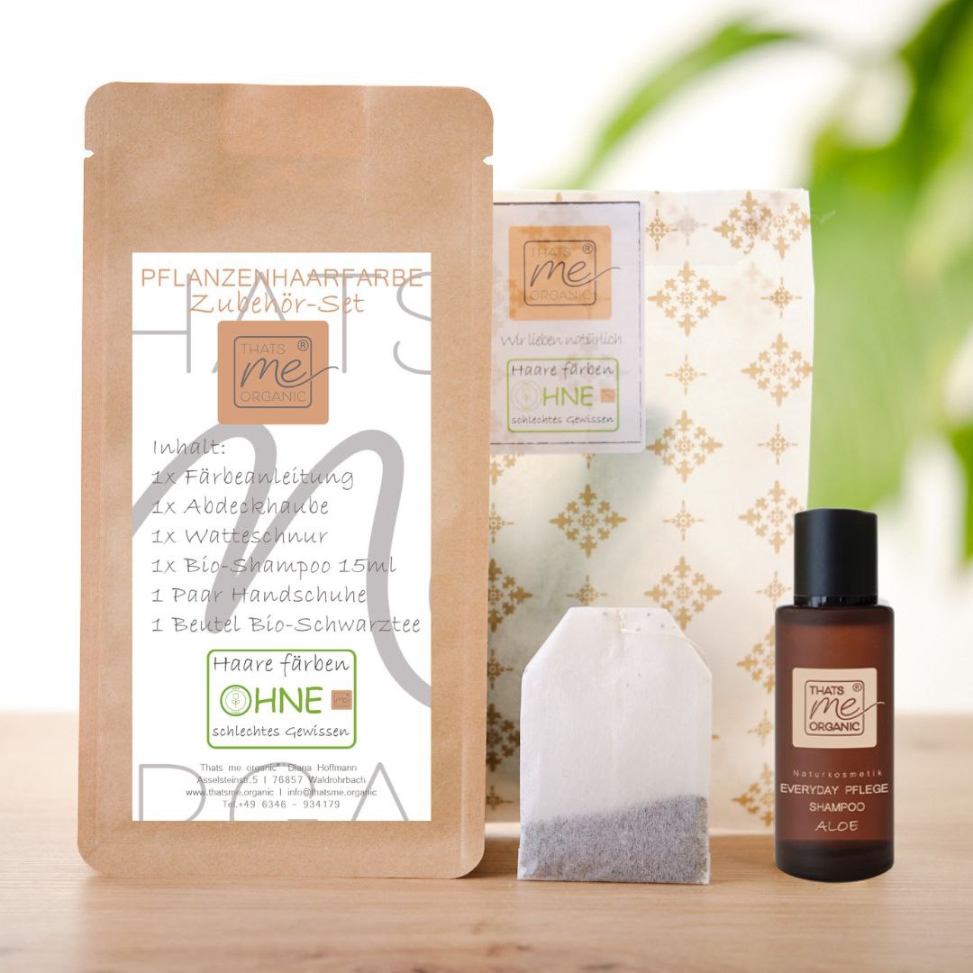 Haarfärbeset auf pflanzlicher Basis mit Flaschen, einem Beutel und einem Päckchen, ausgestellt auf einer Holzfläche.