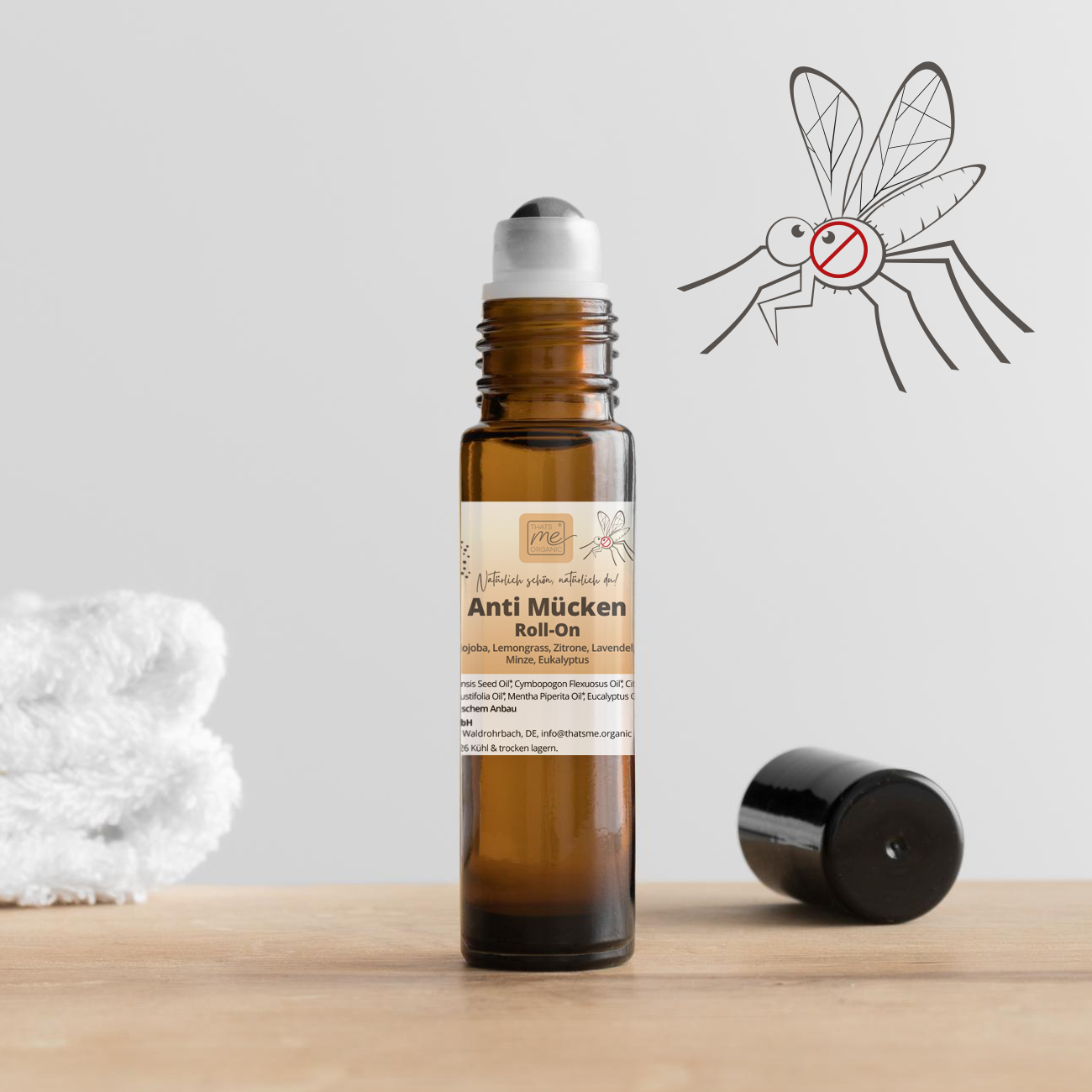 Auf einem Tisch steht eine braune Thats me Organic® Anti-Mücken-Roll-On-Flasche mit der Aufschrift "natürlicher Mückenschutz" und einer Mücken- und No-Symbol-Grafik im Hintergrund.