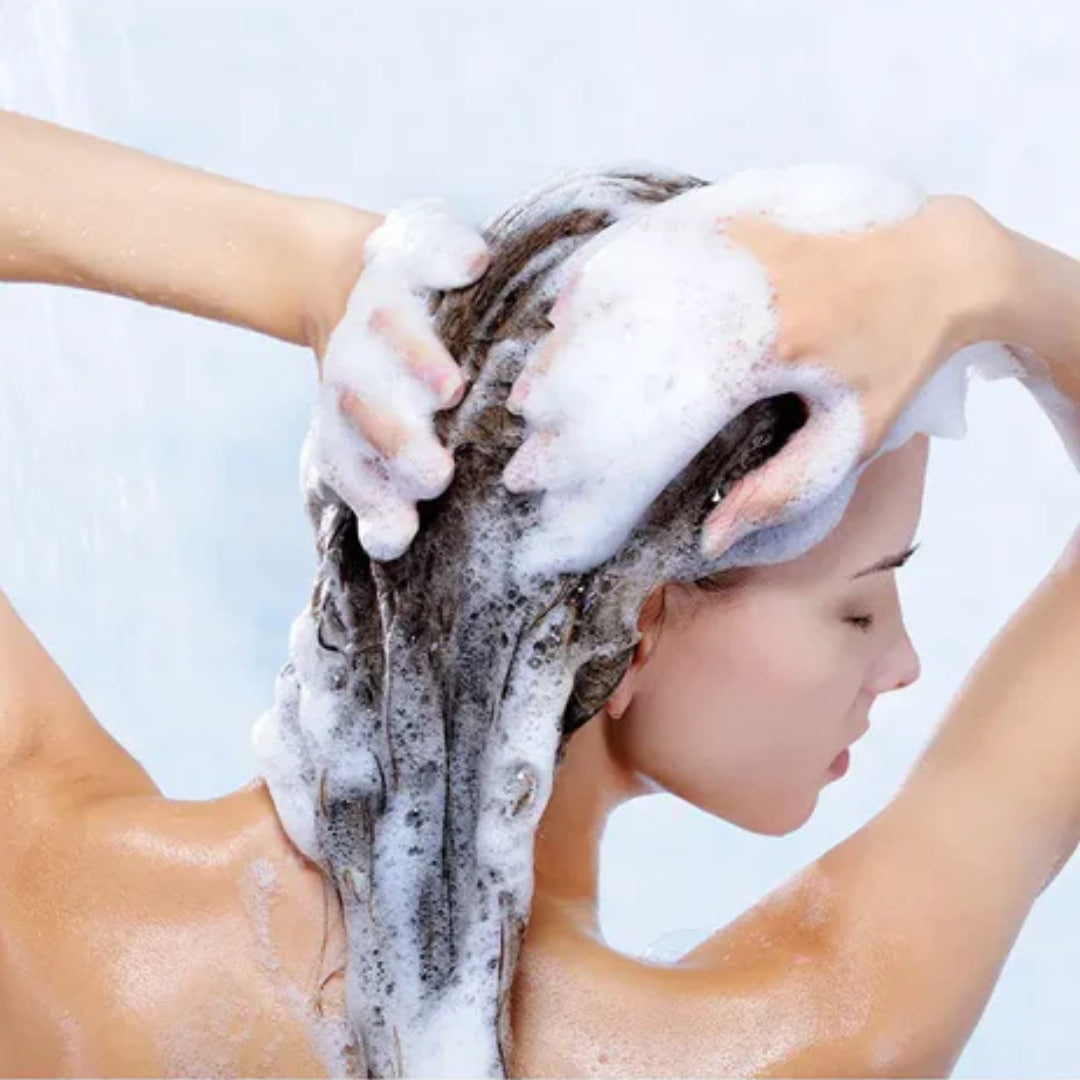 Eine Frau wäscht sich die Haare mit Thats me Organic® Shampoo, das unter der Dusche einen reichhaltigen Schaum erzeugt.