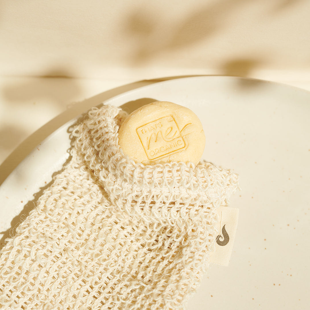 Ein Thats me Organic® Seifenstück mit BIO Arganöl wird in einem Netzbeutel geliefert und befindet sich auf einem weiß gesprenkelten Teller.