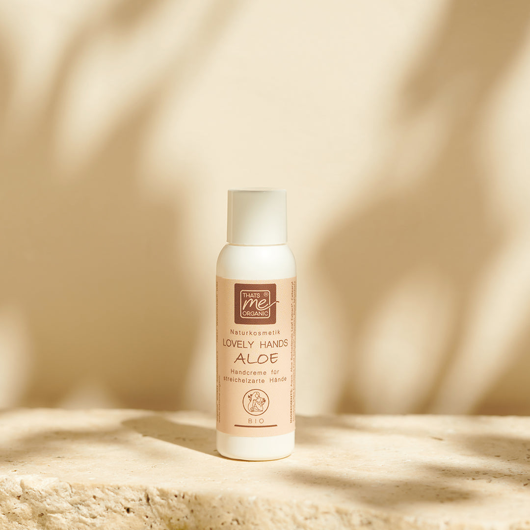 Eine Flasche Thats me Organic® Handcreme mit Hyaluron steht auf einer beigen Steinfläche und wirft weiche Schatten in den Hintergrund.