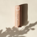 Ein zylindrischer Behälter in Roségold mit der Aufschrift Silver Ionic Brush von Thats me Organic® wirft einen Schatten auf einen cremefarbenen Hintergrund und deutet auf das luxuriöse Profi-Pinsel-Set mit veganen Make-up-Pinseln im Inneren hin.