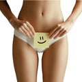Eine Frau in weißer Unterwäsche hält einen Klebezettel mit einem Smiley-Gesicht über ihren Beckenbereich und weist auf die Bedeutung der Intimpflege und die Verwendung von Thats me Organic® natürlicher Intimreiniger zur sanften täglichen Pflege hin.