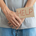 Eine Person hält ein HELP-Zeichen über ihren Unterbauch, um die Bedeutung der Intimpflege und die sanfte Unterstützung durch Thats me Organic® natürlicher Intimreiniger zu betonen.