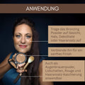 Eine Frau trägt Thats me Organic® veganen Bronzer mit einem Pinsel auf ihr Gesicht auf, hält einen Spiegel und folgt den deutschen Anweisungen. Dieser vegane Bronzer verleiht Ihrer Haut einen natürlichen Glow.