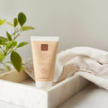 Eine Tube Thats me Organic® Hyaluron Handcreme liegt in einem Marmortablett neben einer grünen Pflanze und einem beigen Tuch.