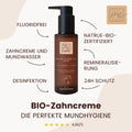 Braune Flasche Thats me organic® BIO-Zahncreme, fluoridfrei und mit Aloe Vera, zeigt die wichtigsten Vorteile auf Deutsch und unterstützt perfekte Mundhygiene vor beigem Hintergrund.