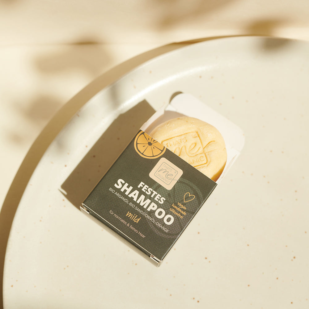 Ein Thats me Organic® BIO Arganöl Shampoo Bar ruht auf einer hellen, gesprenkelten Oberfläche, die von hellem Tageslicht beleuchtet wird.