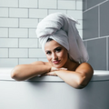 Eine Frau, die sich ein Handtuch um den Kopf gewickelt hat, lächelt, während sie sich in einer weißen Badewanne entspannt und die sanfte Pflege von Thats me Organic® Shampoo für empfindliches Haar genießt.