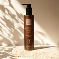 Braune Flasche mit Bio-Aloe-Shampoo mit einer Pumpe, die auf einer Steinfläche im Sonnenlicht steht.